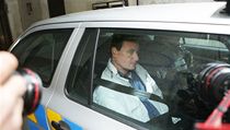 Policejní auto odváží Davida Ratha ze služebny v Dlážděné ulici.